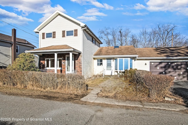 traditional-style house with a garage, brick siding, and covered porch