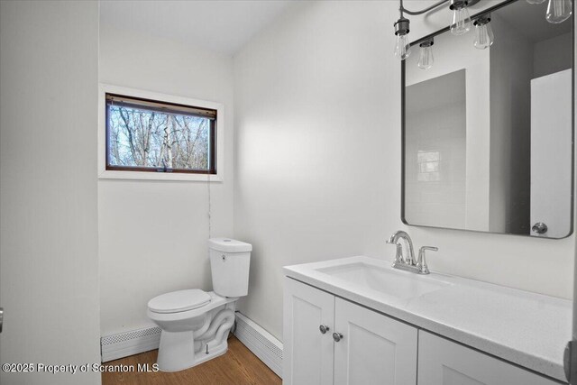bathroom featuring baseboard heating, toilet, vanity, and wood finished floors