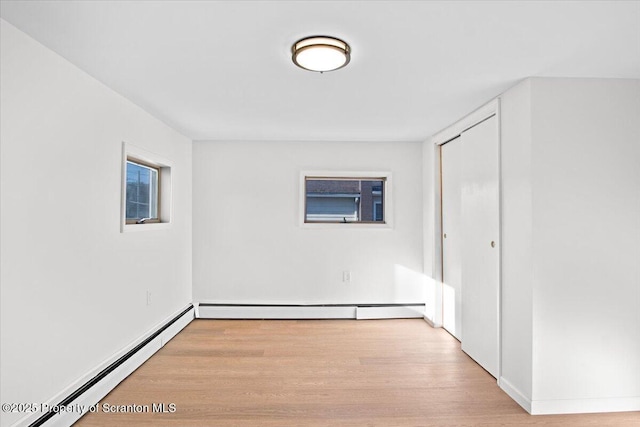 spare room with baseboard heating and wood finished floors