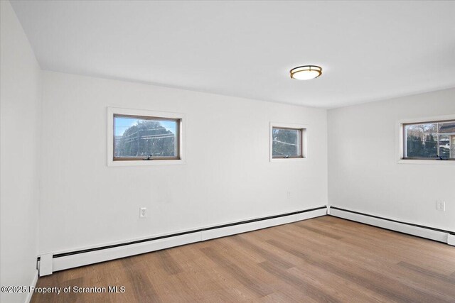 unfurnished room with a baseboard radiator and wood finished floors