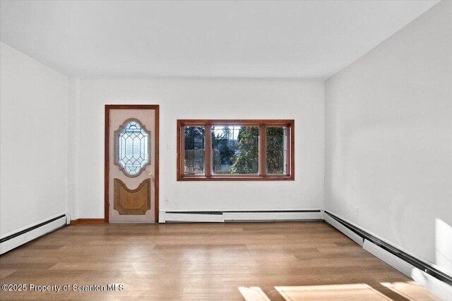 foyer entrance with a baseboard radiator and wood finished floors