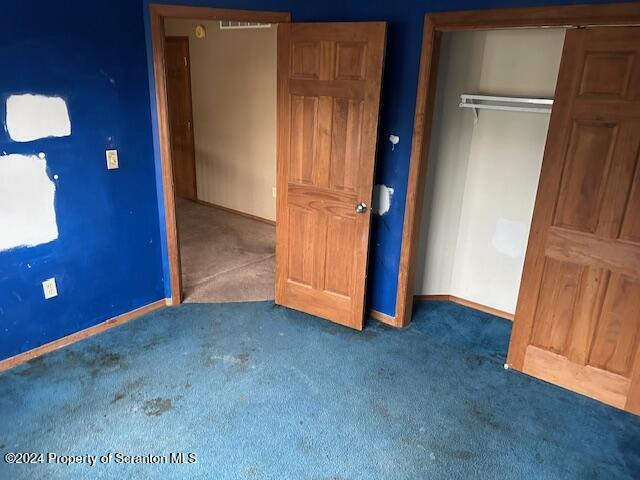 unfurnished bedroom featuring dark carpet and a closet