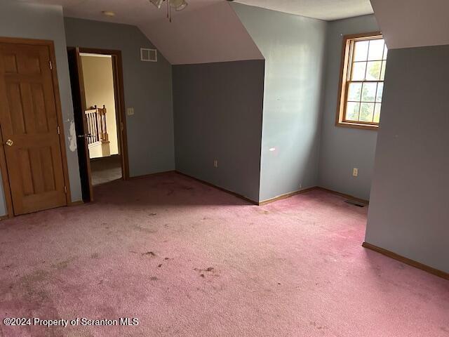 bonus room featuring lofted ceiling and light carpet