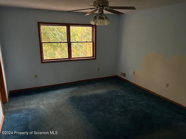 empty room with dark carpet and ceiling fan