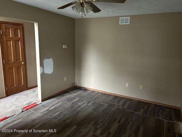 empty room featuring ceiling fan, dark hardwood / wood-style floors, and a textured ceiling