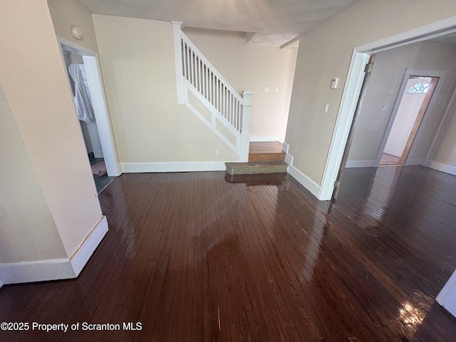 unfurnished living room featuring baseboards, wood-type flooring, and stairs