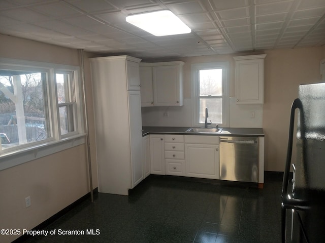 kitchen with white cabinetry, freestanding refrigerator, a sink, dishwasher, and dark countertops