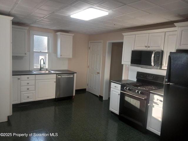 kitchen with dark countertops, white cabinets, black appliances, and a sink