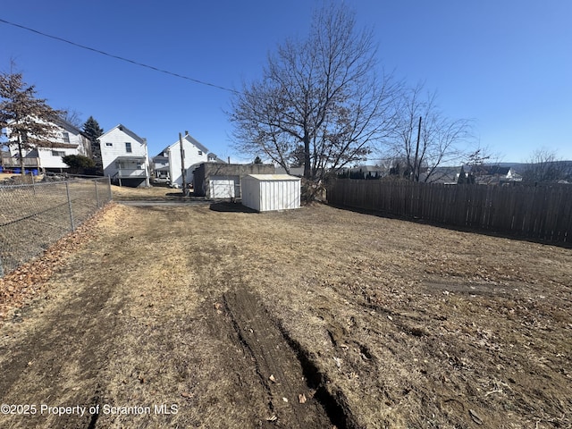 view of yard with an outbuilding, a storage unit, and fence