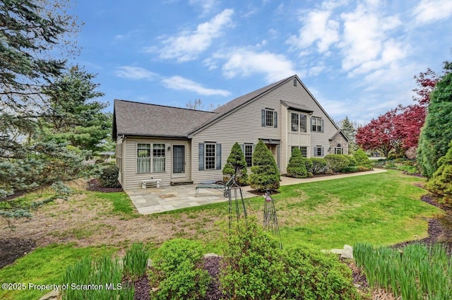 back of house featuring a lawn, a shingled roof, and a patio area