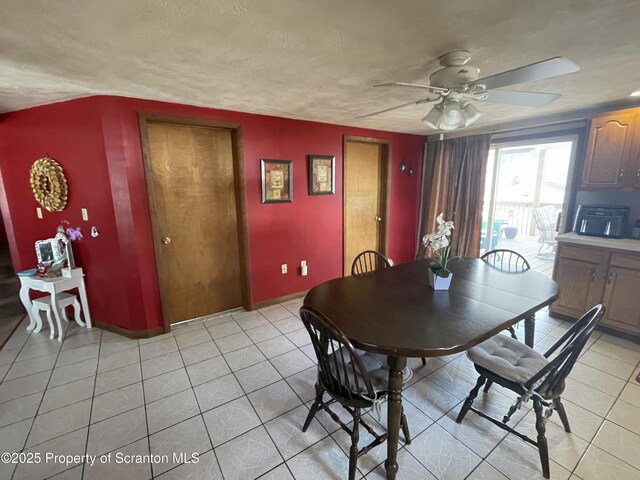 dining area featuring ceiling fan, light tile patterned flooring, baseboards, and a textured ceiling