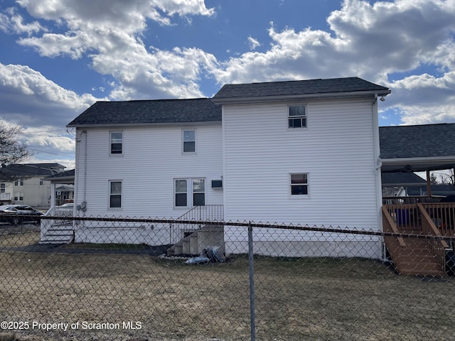 rear view of property with roof with shingles and fence