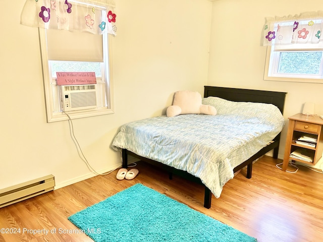 bedroom featuring baseboard heating, cooling unit, and hardwood / wood-style flooring