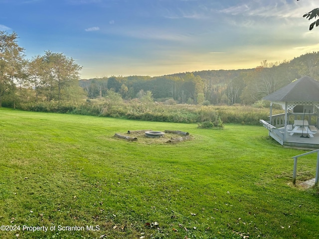 yard at dusk with a deck and an outdoor fire pit