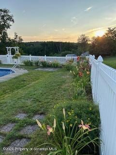 yard at dusk with a fenced in pool and a water view