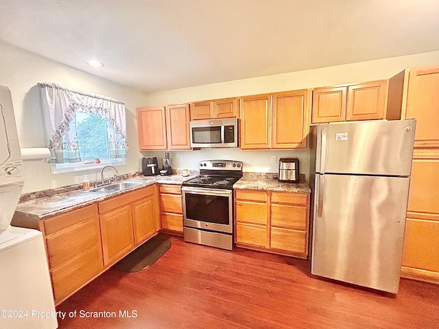 kitchen featuring light wood-type flooring, stainless steel appliances, stacked washer / drying machine, and sink