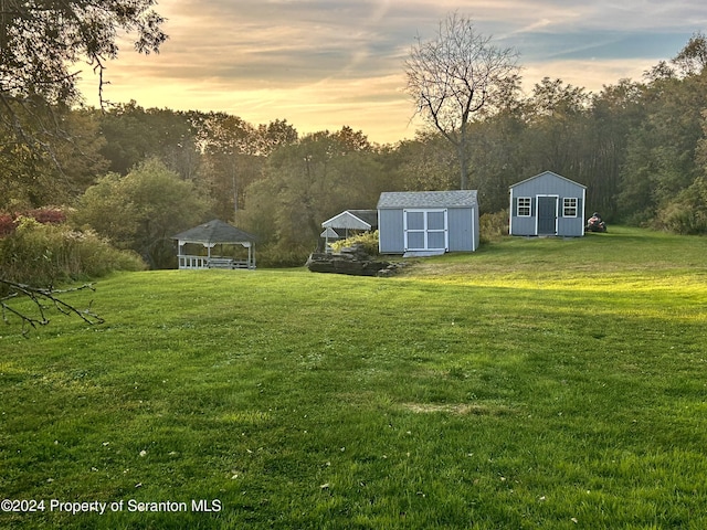 yard at dusk featuring a gazebo and a storage shed