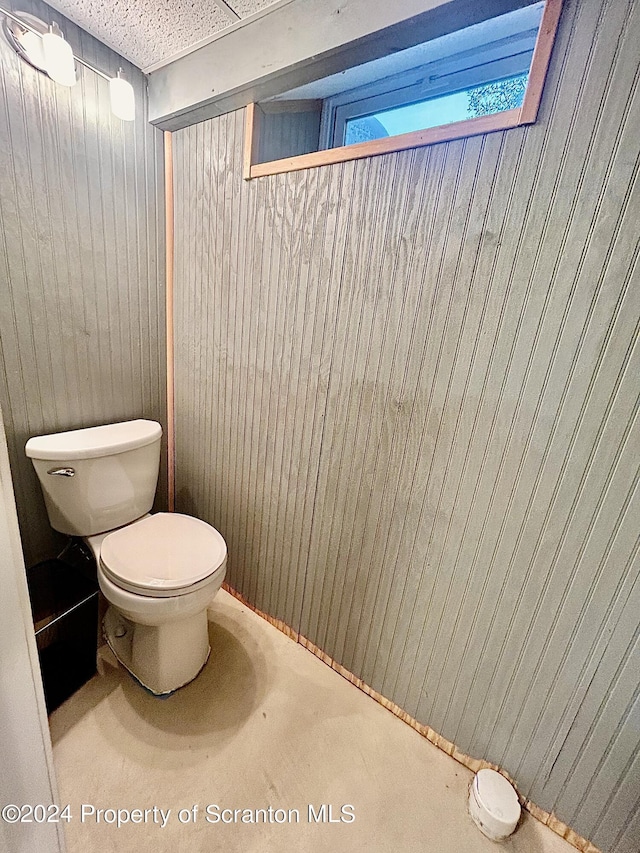 bathroom with toilet and wooden walls