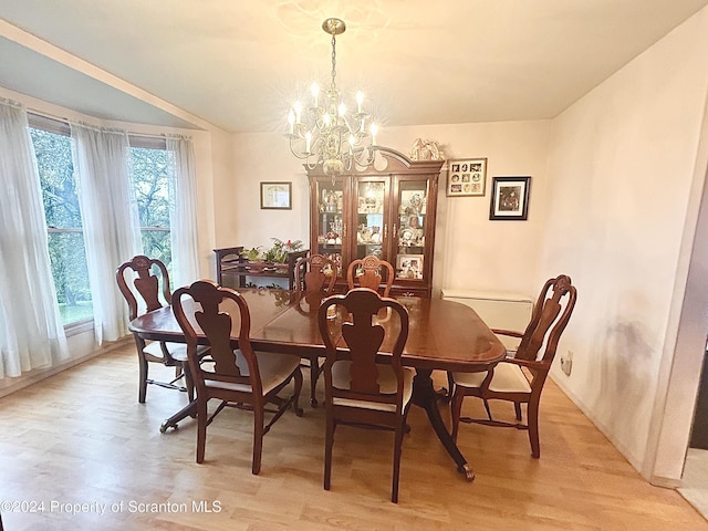 dining space with light hardwood / wood-style flooring and a notable chandelier