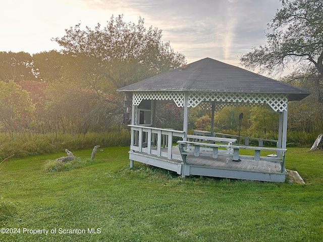 deck at dusk featuring a gazebo and a lawn