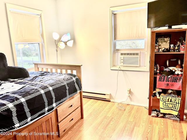 bedroom with light wood-type flooring, baseboard heating, and cooling unit