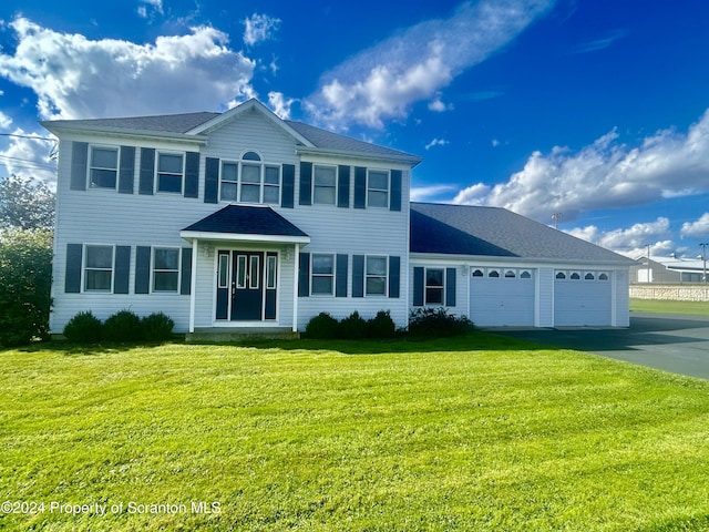 colonial inspired home featuring a garage and a front yard