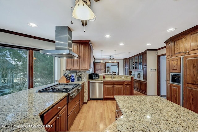 kitchen featuring island exhaust hood, appliances with stainless steel finishes, light stone countertops, and ornamental molding