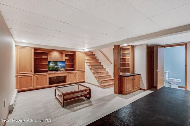 unfurnished living room with baseboard heating, a paneled ceiling, and light hardwood / wood-style flooring