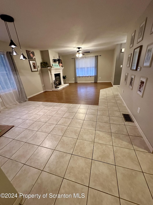 unfurnished living room with light tile patterned floors and ceiling fan