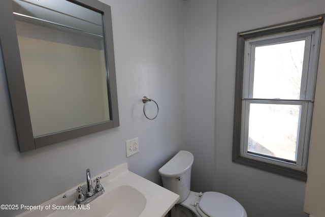 half bathroom with toilet, plenty of natural light, and vanity