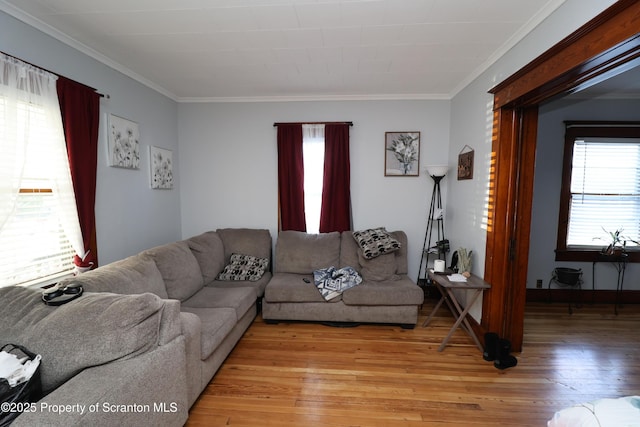 living area with crown molding, light wood-style floors, and baseboards