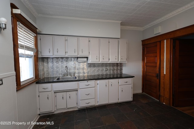 kitchen featuring a sink, dark countertops, and white cabinets