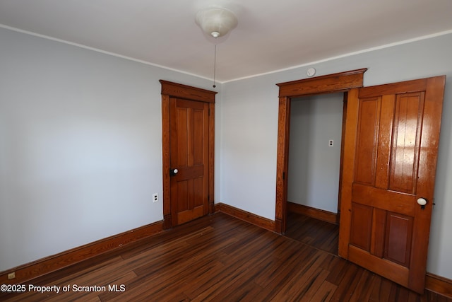 empty room featuring dark wood-type flooring and baseboards