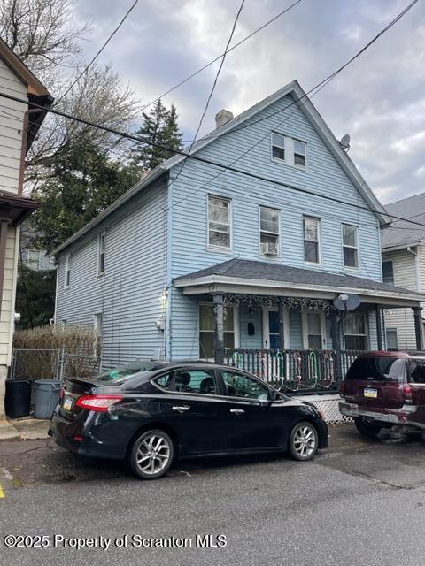 view of front of home featuring a chimney and covered porch