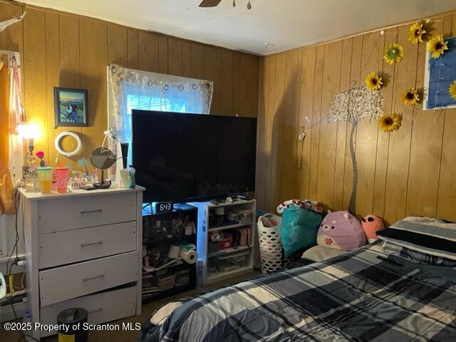 bedroom with a ceiling fan and wood walls