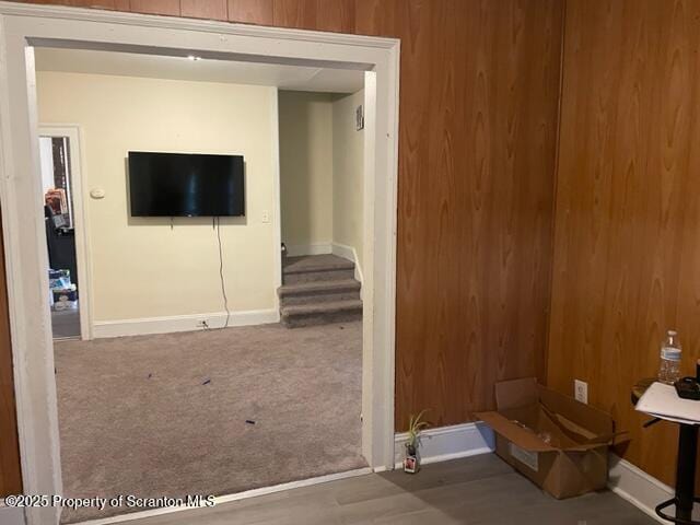 carpeted living area with wood walls and baseboards