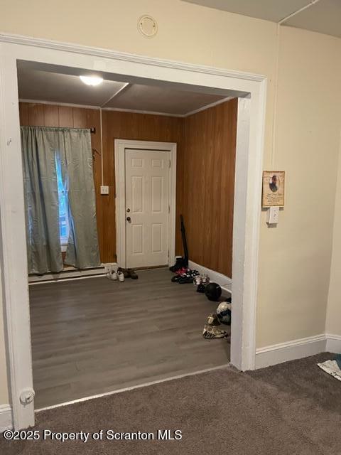 interior space with baseboards, wood walls, and wood finished floors
