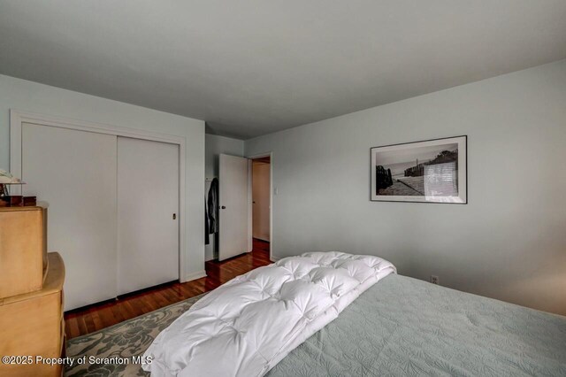 bedroom featuring a closet and dark wood-style flooring