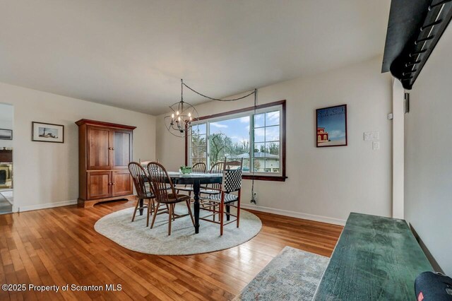 dining room with a chandelier, light wood-style flooring, and baseboards