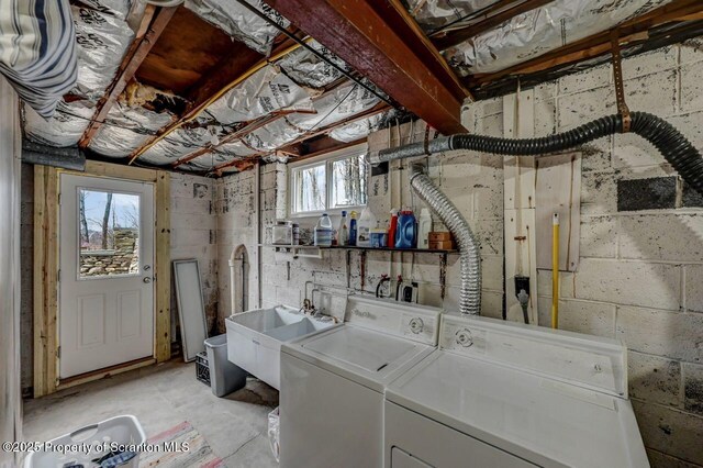 clothes washing area featuring laundry area, washing machine and dryer, and a sink