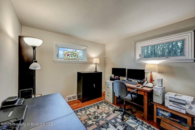 office area with baseboards, visible vents, and wood finished floors