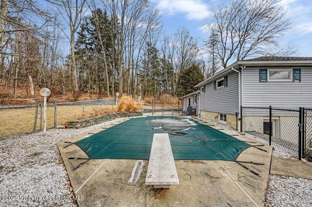 view of swimming pool featuring fence, a diving board, and a fenced in pool