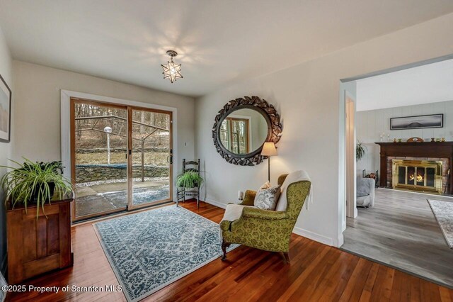 sitting room with a glass covered fireplace, wood finished floors, and baseboards