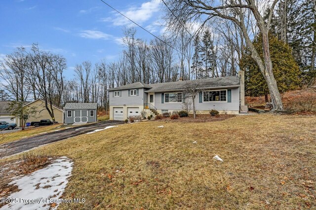 view of front of home featuring a garage, driveway, a front lawn, and an outbuilding