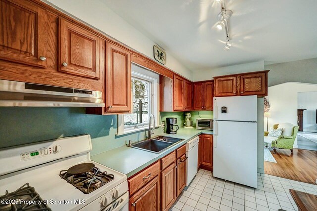 kitchen featuring light tile patterned floors, under cabinet range hood, white appliances, a sink, and light countertops