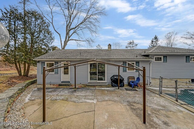 rear view of house with entry steps, fence, roof with shingles, a chimney, and a patio area