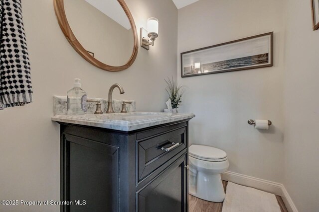 bathroom with baseboards, vanity, toilet, and wood finished floors