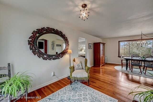 living area with an inviting chandelier, baseboards, and wood finished floors