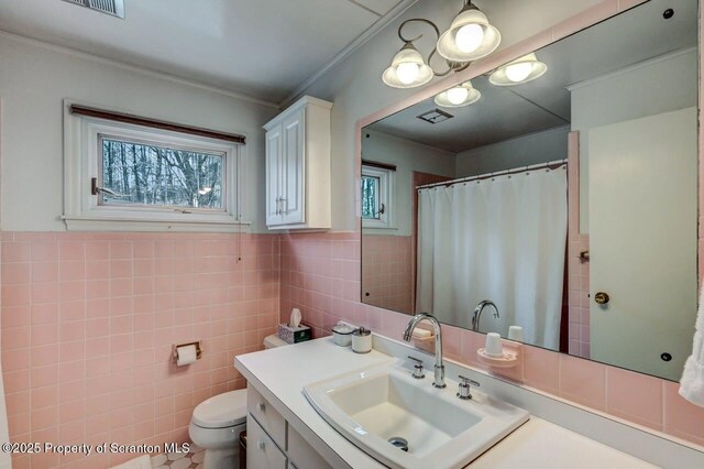 full bathroom featuring tile walls, visible vents, toilet, wainscoting, and vanity