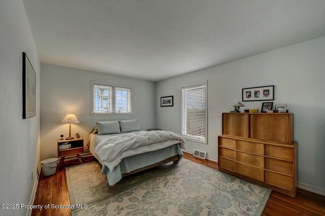 bedroom featuring visible vents, baseboards, and wood finished floors